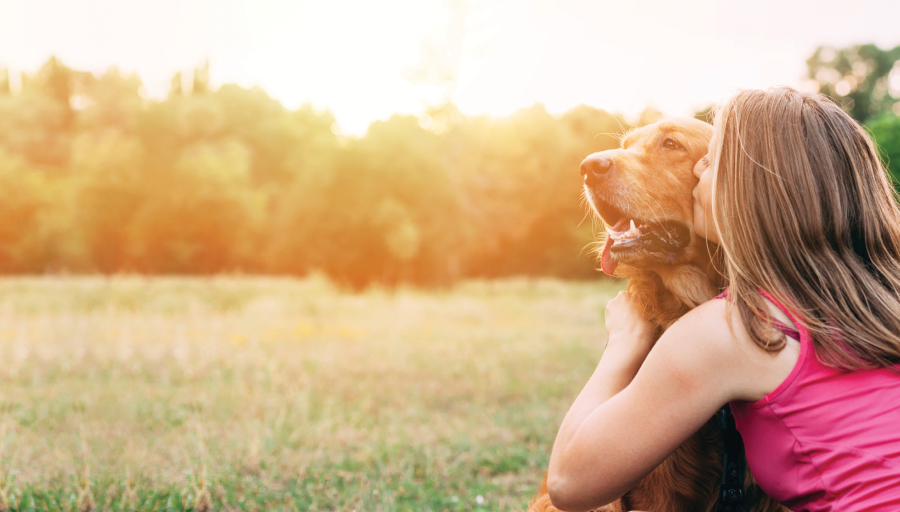 O femeie stătea cu câinele ei afară, pe un câmp, sărutându-i fața