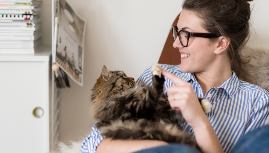 O femeie stătea cu pisica în poală atingându-i laba cu degetul