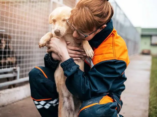 femeie îmbrățișând un pui de câine