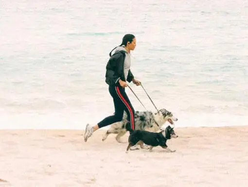 femeie alergând pe plajă cu câinele său